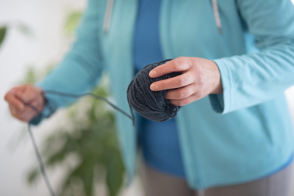Frau hält schwarzen Wollknäuel